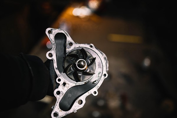 Automotive water pump of the engine cooling system in the hands of an auto mechanic