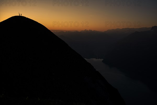 Mountaineer on ridge with Swiss mountains and Lake Thun in the background at sunrise