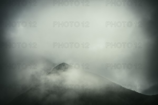 Mountaineer on mountain ridge with dramatic clouds