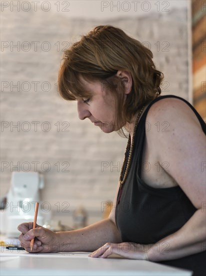 A fashion designer drawing a fashion sketch. Vertical shot