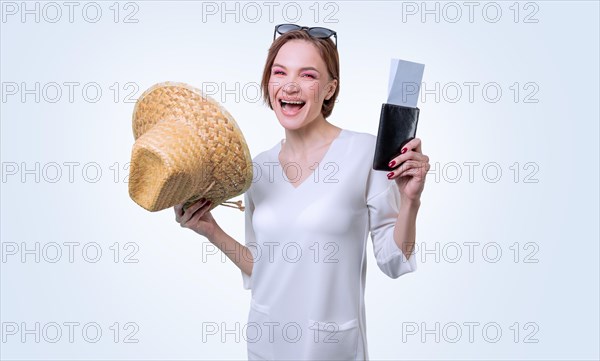 Beautiful girl posing on a white background in a yellow hat with a passport and boarding pass. Tourism concept.