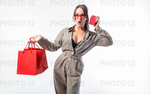 Charming brunette in glasses posing in the studio with red bags and a box for jewelry. White background. Shopping concept.