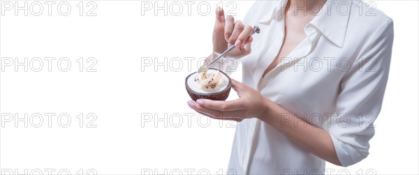 Woman posing in studio with natural coconuts in which dessert is served. Organic food.