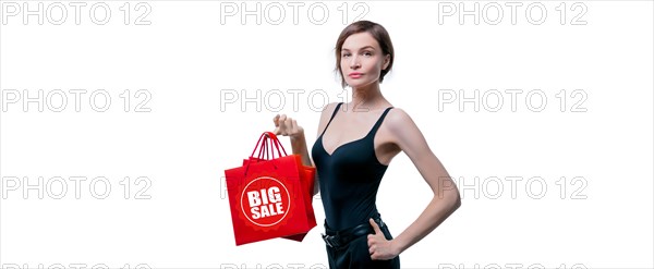 Portrait of stylish adult woman posing in studio on white background with red gift bag. Valentine's Day concept. Holidays and gifts.