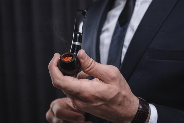 Image of male hands holding a smoking pipe. Tobacco smoking concept.