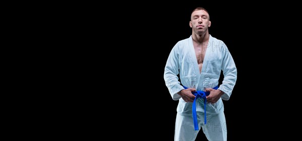 Professional athlete stands in the gym in a kimono with a blue belt. Concept of karate