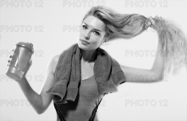 Charming model posing in the studio with a shaker in her hands and a towel around her neck.