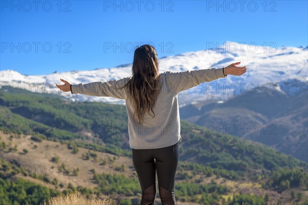 Hiker on her back with arms outstretched happily enjoying the scenery while walking outdoors in winter