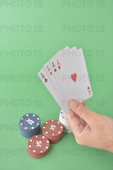 Four aces fan out in a hand above stacked poker chips on a green surface
