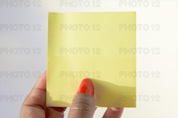 Woman's hand with painted nails holding blank letter paper on pure white background
