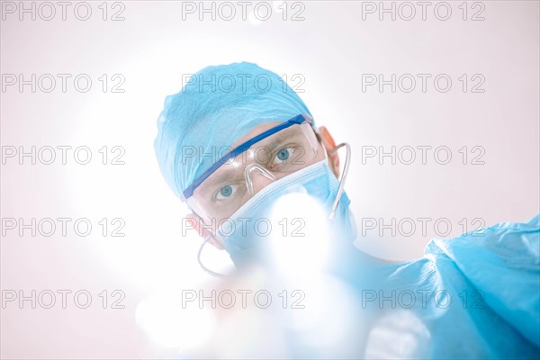 Male surgeon doctor in the operating room looking at the patient at the camera