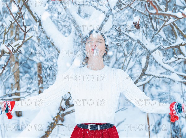 Portrait of a charming girl who stands under a snowy tree. Concept of Christmas