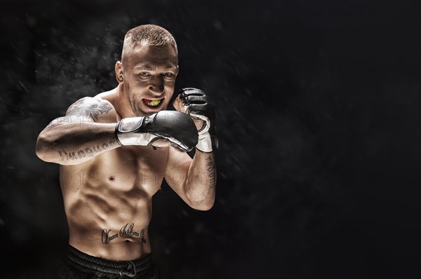 Mixed martial artist posing on a black background. Concept of mma