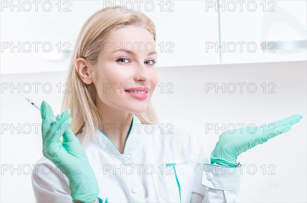 Portrait of a blonde girl in a medical gown with a syringe in her hands. Medical center advertisement.