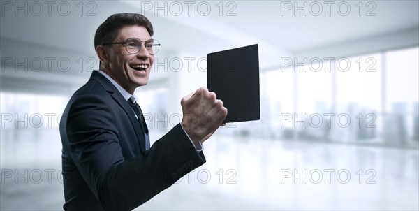 Man with a tablet in his hand screams with joy in the office. The concept of achieving success in business.