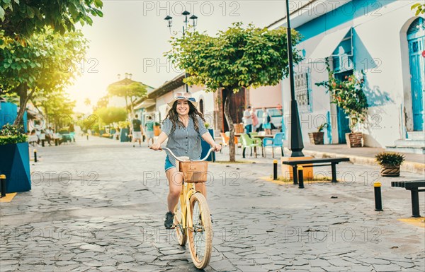 Smiling tourist woman riding a bicycle on the streets of Granada. Beautiful girl riding a bicycle on the street of La Calzada
