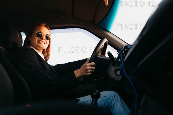 Young beautiful stylish girl driver in a jacket and sunglasses driving a car