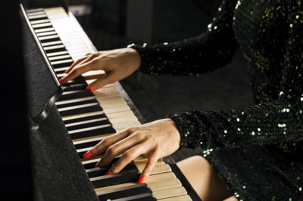 The charming girl in an evening dress plays the old German piano. Front view.