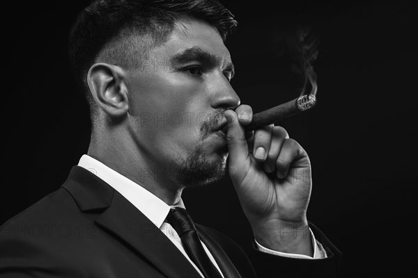 Portrait of a stylish man in a suit with a cigar. Business concept.