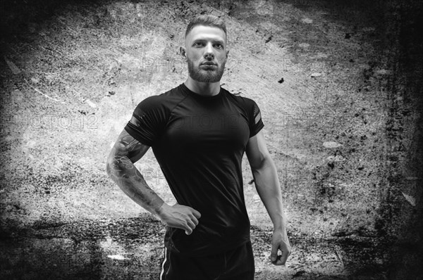 Young muscular guy posing against the background of a concrete wall. Fitness and nutrition concept.