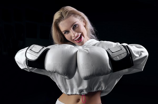 Cheerful and charming girl in a white sweatshirt poses with huge white gloves. The concept of sports