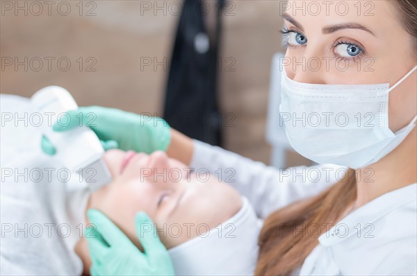 Portrait of a beautician who cleans the patient's face with an ultrasound device. Beauty salons concept.