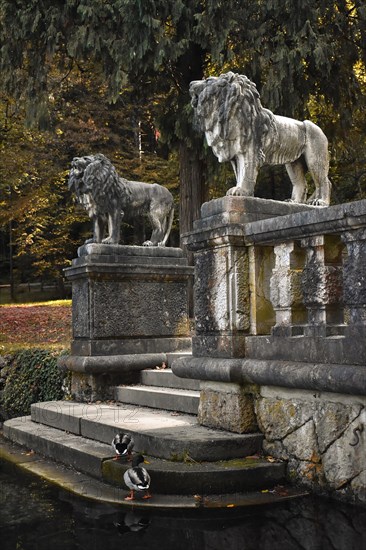 Two lion statues on a stone staircase leading to a small pond