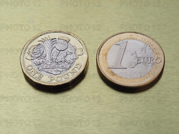 1 pound and 1 euro coin over metal background