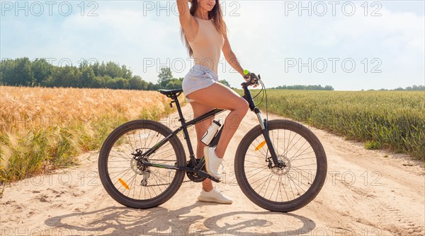 Impersonal portrait of a woman in nature with a bicycle. Recreation and tourism concept.