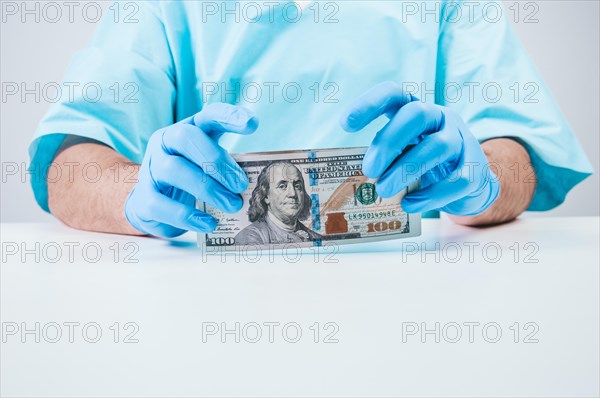 Doctor holds one hundred dollar bills. The concept of corruption in medicine.