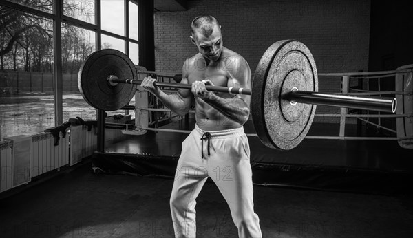 Handsome young man working out with a barbell in the gym. Biceps pumping. Fitness and bodybuilding concept.