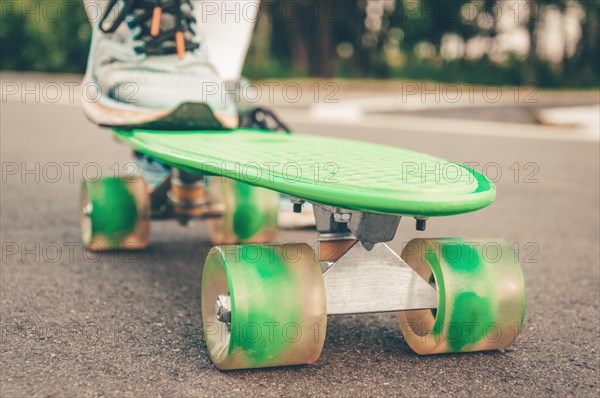 Images of a leg standing on a skateboard. Sunny evening in the park. Skateboarding concept.