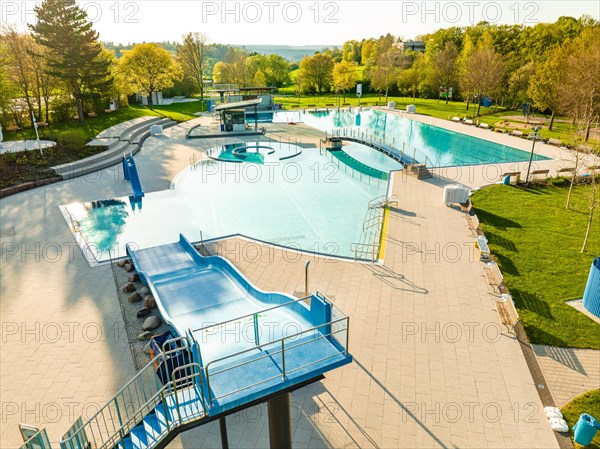 Drone image of a swimming pool with water basin and slides at sunset