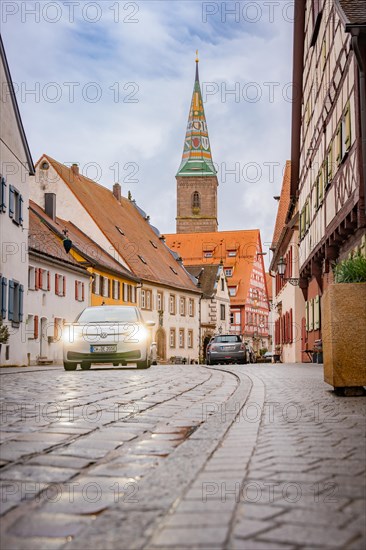 Deer E- Carsharing car in a street with cobblestones in front of a church