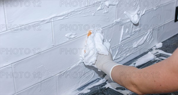 Cleaning ceramic tiles at home with a cleaning agent in a glove