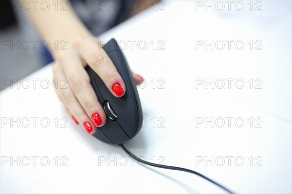 Girl's hand uses a vertical ergonomic joystick of a computer mouse. working at the computer