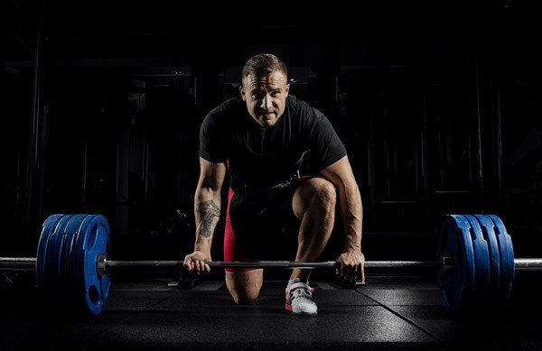 Professional athlete bent over the barbell and is preparing to lift a very heavy weight. Front view