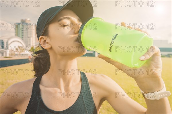 Image of a girl drinking from a bottle after a run. Running concept.