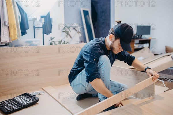 Young handsome carpenter assembling a wardrobe at a customer's home