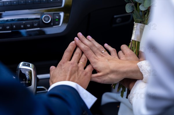 Hands of bride and groom with rings in a car at a beautiful wedding
