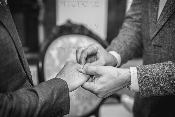 Gay wedding groom placing ring on husband at ceremony