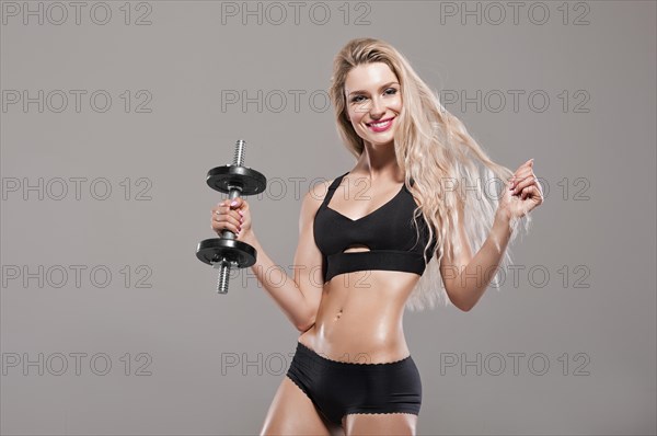 Beautiful athlete posing with a dumbbell in the studio.