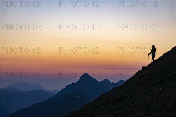 Mountaineer on mountain ridge with Rothorn peak in the background at blue hour