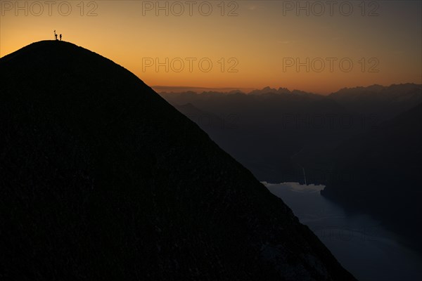 Mountaineer on ridge with Swiss mountains and Lake Thun in the background at sunrise