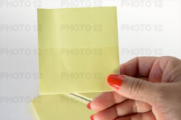 Woman's hand with painted nails holding blank letter paper on pure white background