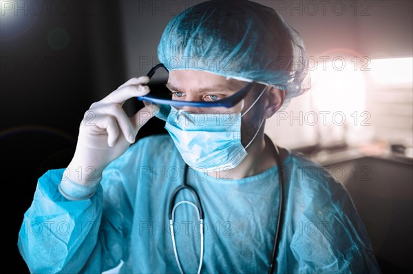 Male scientist doctor working in a laboratory with a monitor in a sterile uniform and glasses