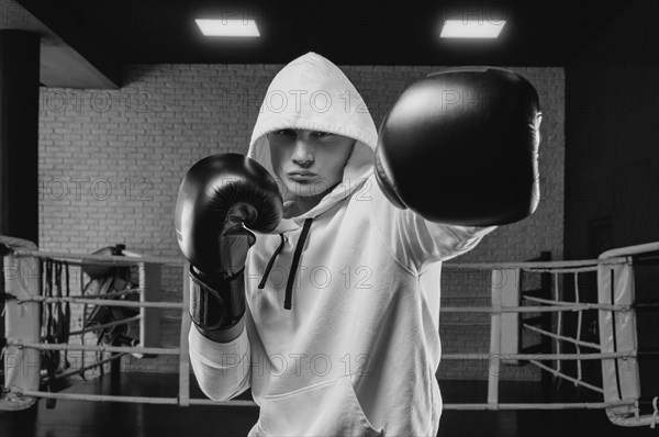 Brutal athlete boxing in the ring in a white hoodie covered with a hood. Mixed martial arts concept. High image quality