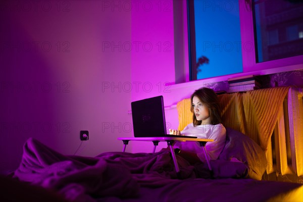 A young pretty girl works at home on a laptop