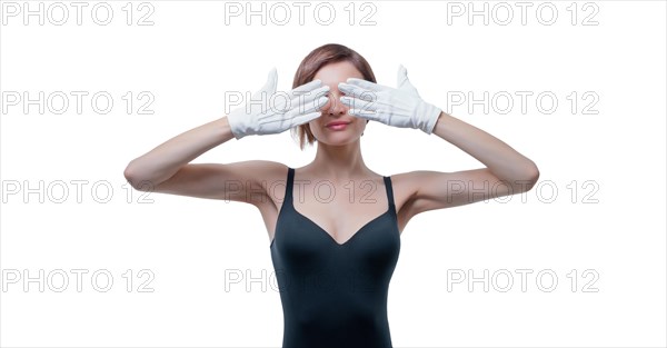 Beautiful young woman in white gloves covered her eyes with her hands