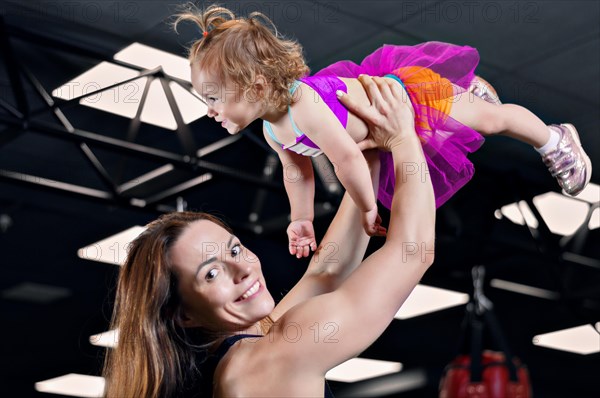 Mom throws her daughter up in the gym.